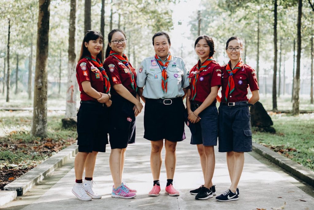 A group of young scout leaders posing in uniform in a forest setting, showcasing teamwork and unity.